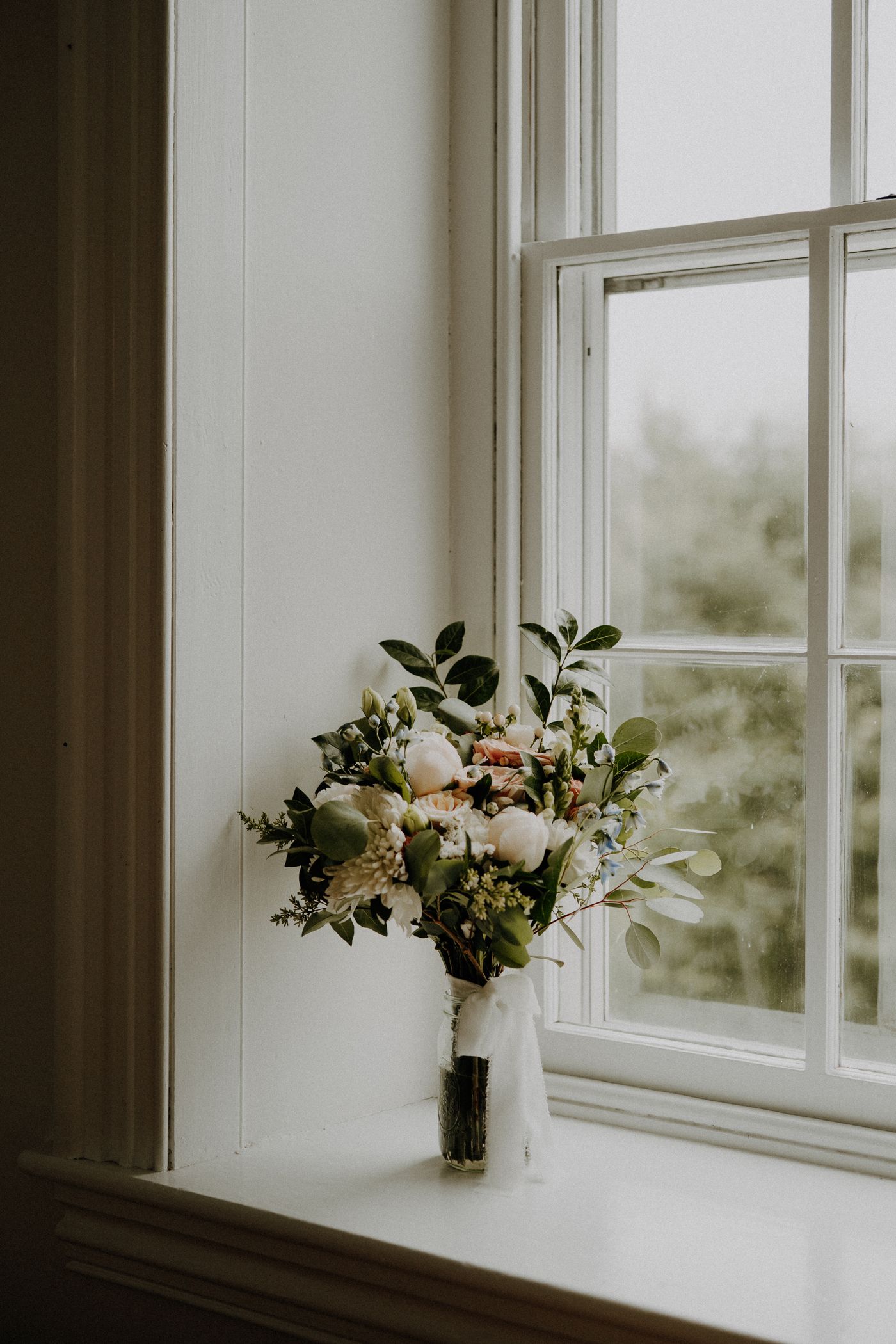 Soft wedding florals beside a sunlit window